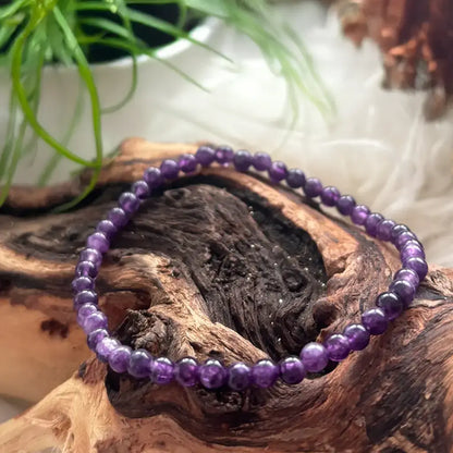 Nahaufnahme von Amethyst Armband mit runden Perlen auf Naturholz – kraftvoller Begleiter für Meditation & Raumharmonie.
