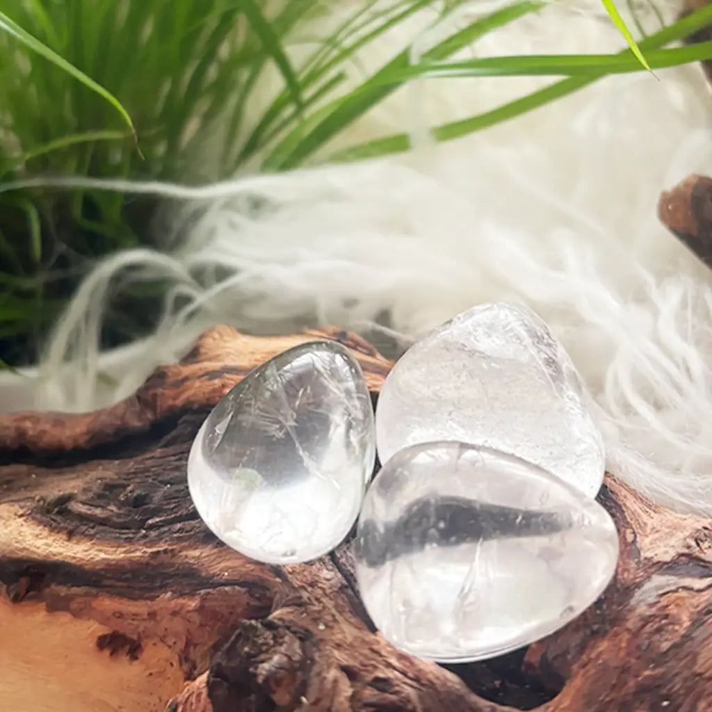 Detailaufnahme drei Bergkristall Trommelsteine – transparente, polierte Kraftsteine mit natürlicher Struktur auf Holzdeko