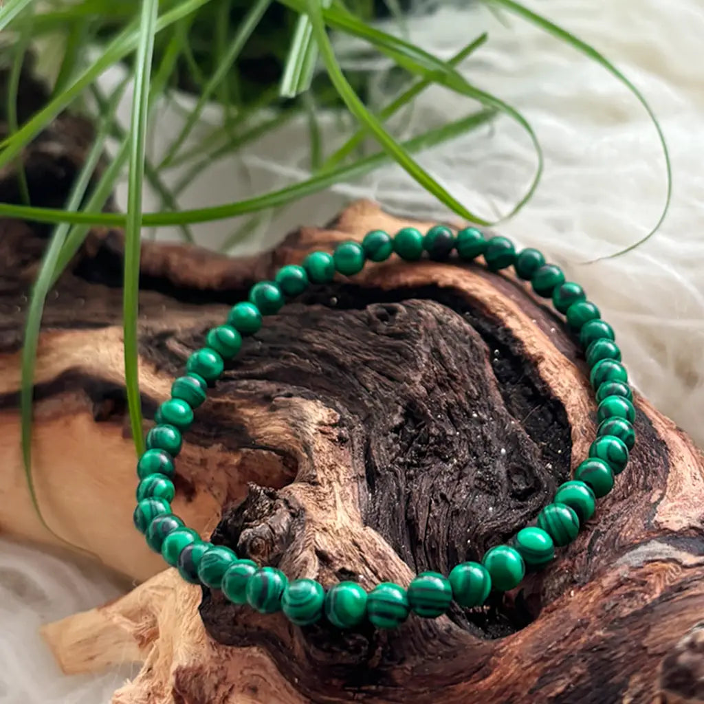 Detailansicht eines feinen Malachit Armbands aus 4mm Kugelperlen mit intensiver grüner Maserung auf hellem Naturhintergrund
